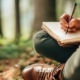 Person sitting cross-legged outdoors, writing in a journal